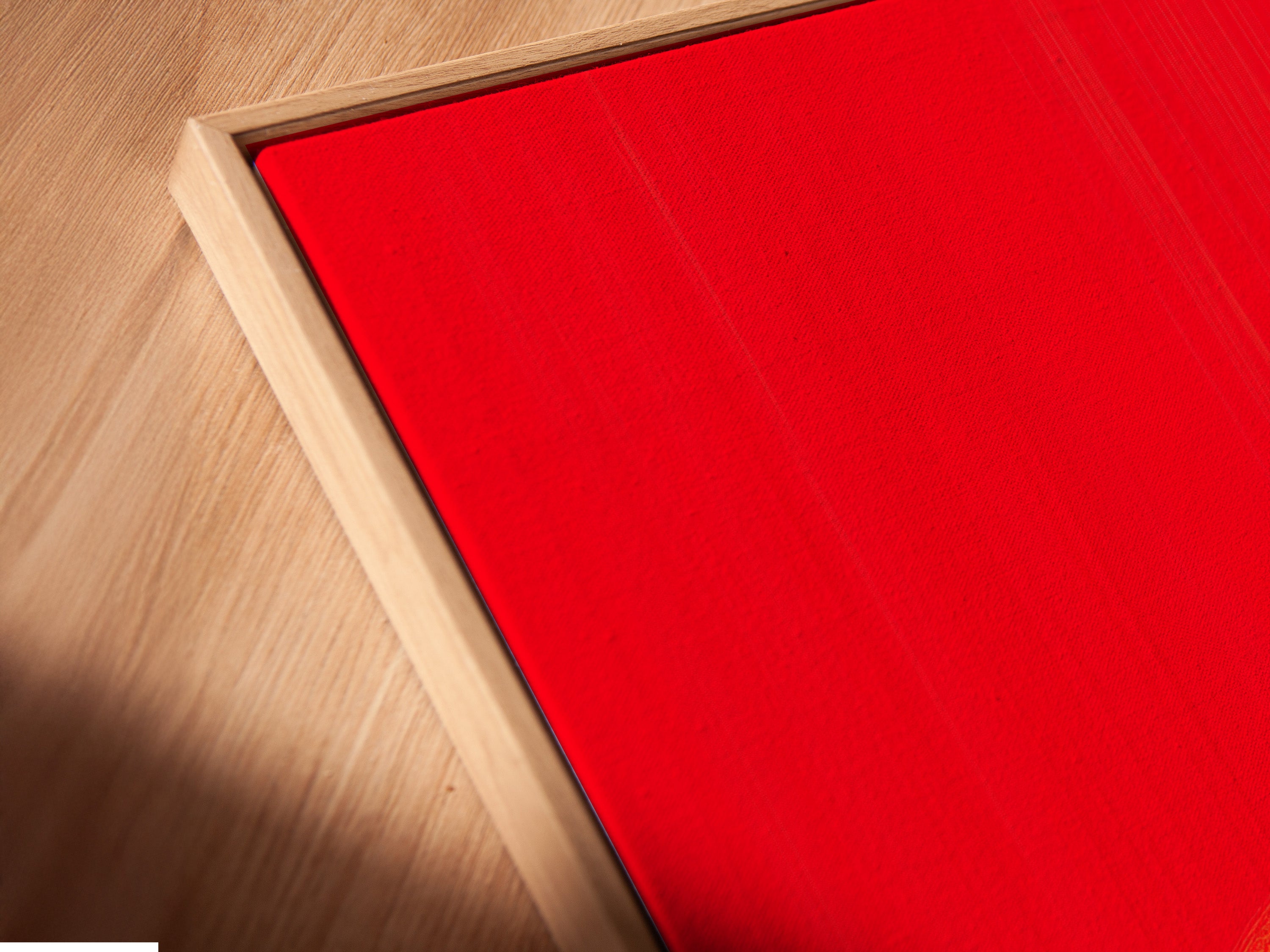 A close up of a Cowboy Sunset Canvas Print in a floating frame. The red orange silhouette pops against the light wall. This western artwork is perfect for rustic themed spaces. Enhance your home decor with this unique piece.