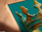 Angled close up of a canvas print in a floating frame. The artwork features a crown with dripping paint or glaze. The colors are gold blue and teal. The floating frame gives the art a modern gallery look. This artwork is ready to hang and enjoy.
