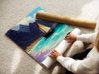 A woman rolling a fine art poster paper print of sailboat art. The coastal print features a seascape canvas. Teal artwork enhances beach art. Ocean view art in a beige tone. Perfect sailing decor for any room.