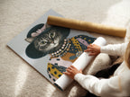A woman is carefully rolling a fine art poster paper. She is preparing a vintage cat portrait art print. This whimsical animal wall art is ready to be displayed. It is perfect for adding to bohemian styles.