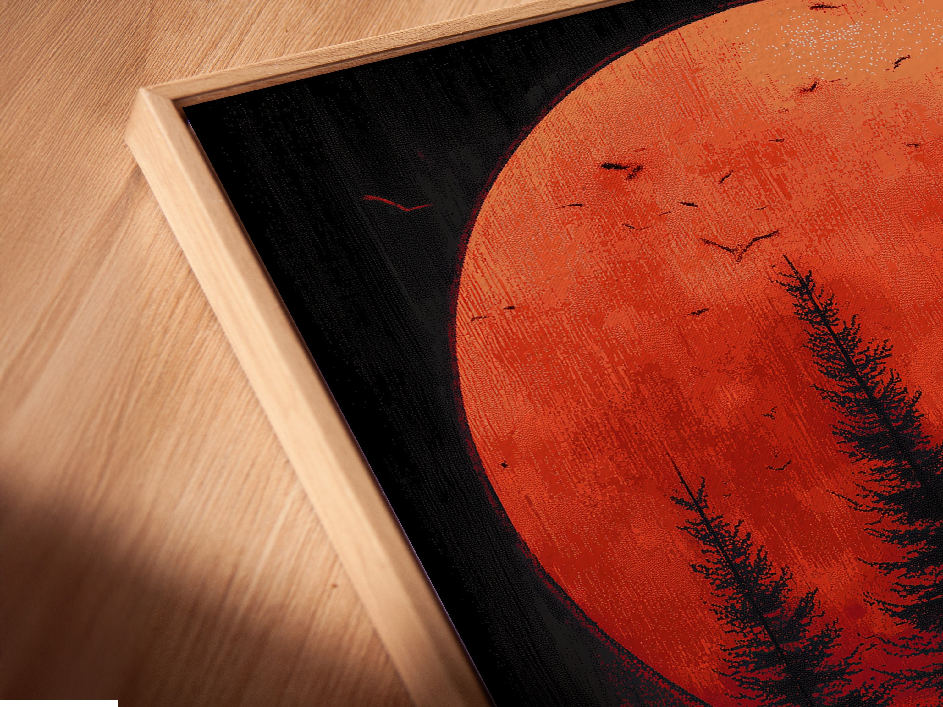 A close up angled view reveals a canvas print in a floating frame. The forest moon art and red sunset print create a captivating scene. This piece of woodland wall decor is perfect for a contemporary space. The floating frame adds a modern touch.