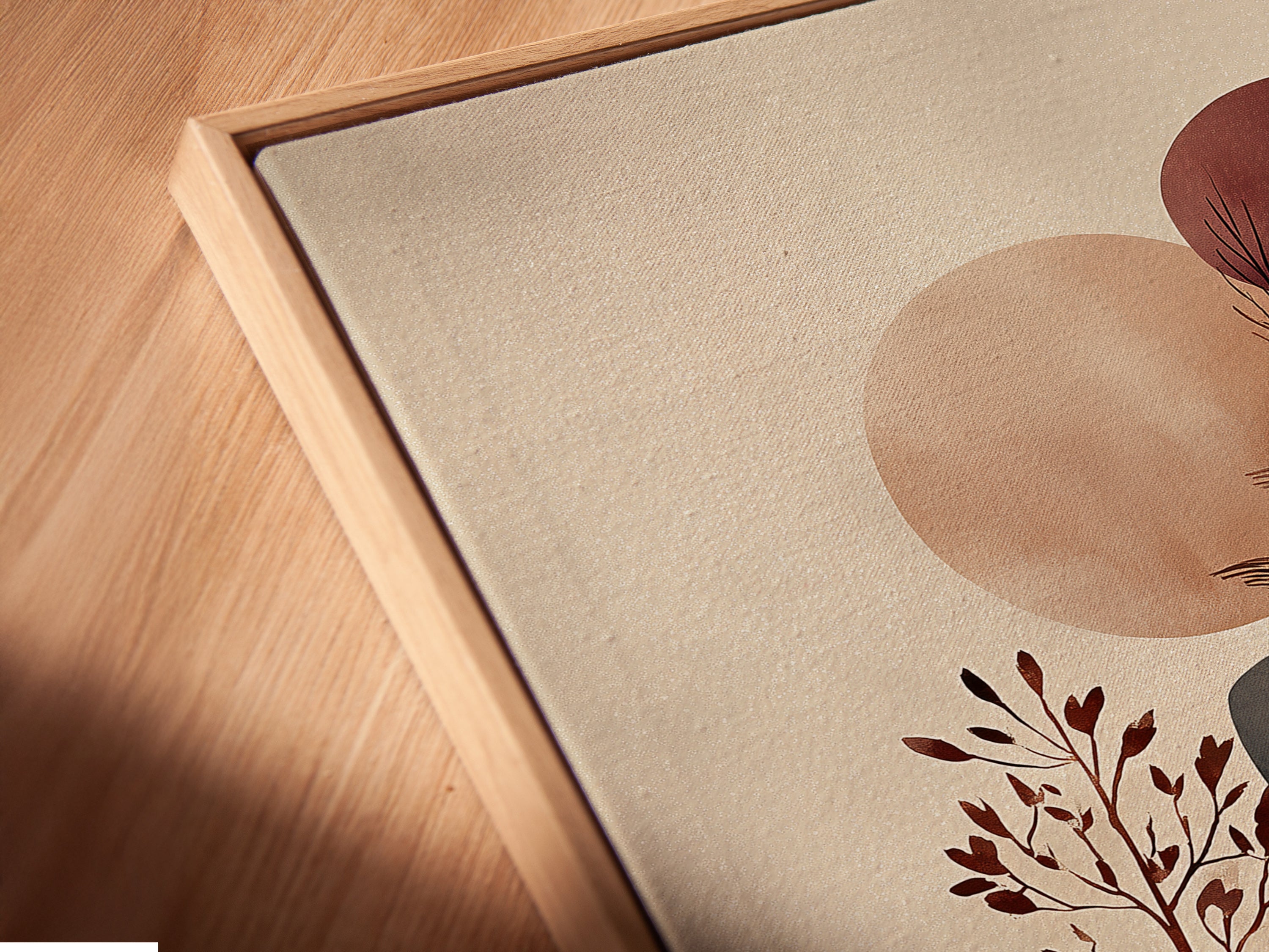 Close-up of an angled canvas print in a floating frame. This abstract botanical artwork features earth tones. Perfect for a modern boho style living room. The floating frame enhances the artwork's visual appeal. This canvas print adds a touch of nature to your space. Enjoy a fine art poster.