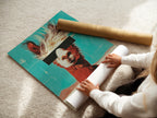 A woman is carefully rolling a fine art poster paper. The paper features a llama artwork. It is ready to be framed or hung as is. The poster showcases retro teal and orange colors.