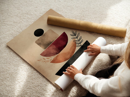 A woman is carefully rolling a fine art poster paper. The paper will showcase abstract artwork with terracotta geometric shapes and neutral tones. This high-quality print is perfect for modern minimalist art. It also enhances scandi and boho decor.