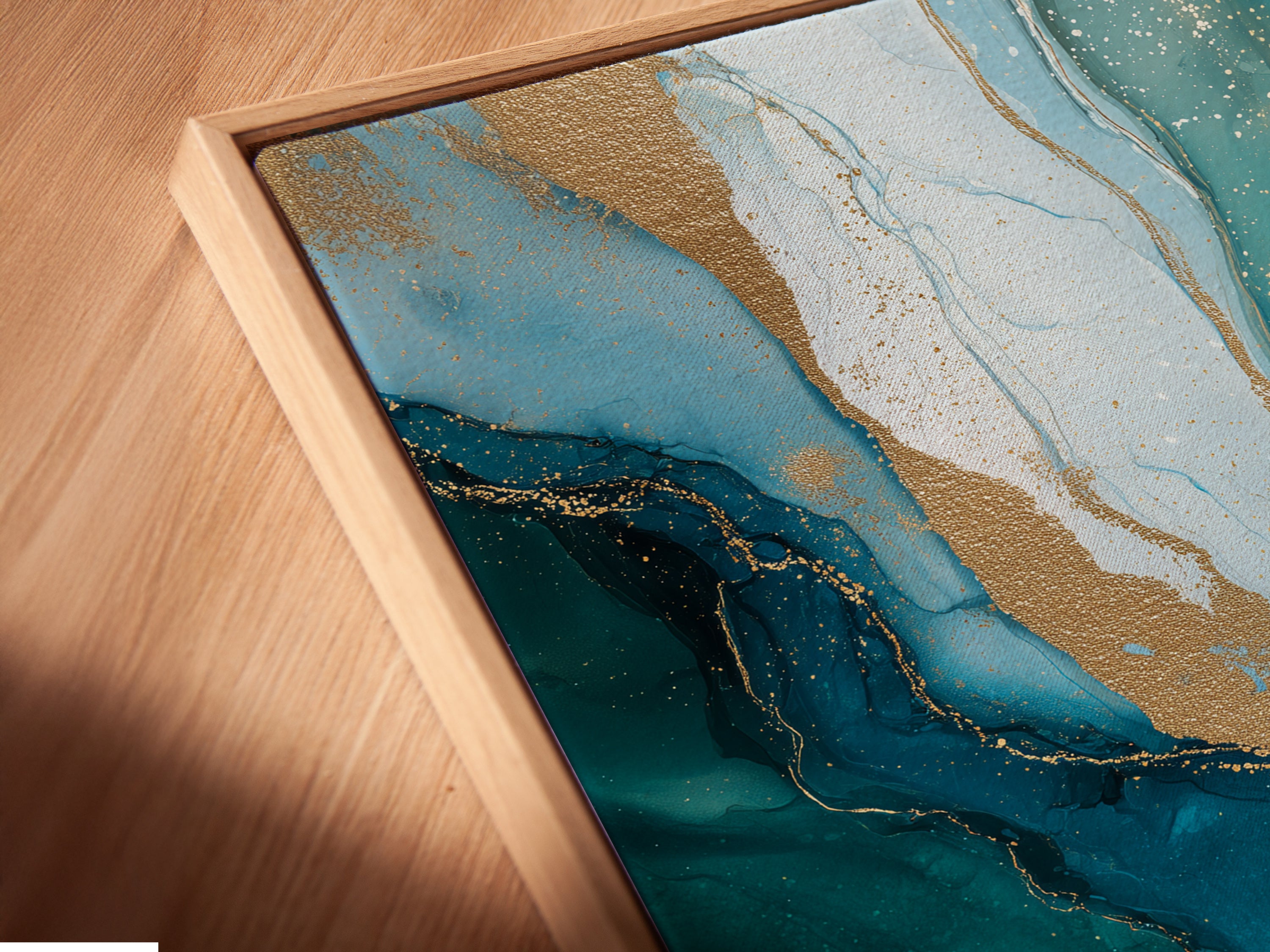 A close up angled view showcases the canvas print in a floating frame. The floating frame enhances the contemporary look of the artwork. See the fine details of the teal blue and gold artwork. Discover the beauty of modern wall decor.