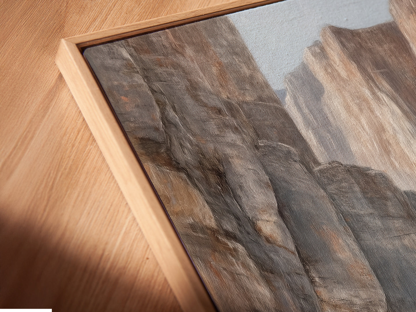 A close-up angled view of a Canyon River canvas print in a floating frame. This desert landscape artwork appears to float on the wall. Neutral tones and a floating frame create a modern look. Ideal for showcasing earth tone art. Explore the beauty of this nature painting. Perfect for any room.