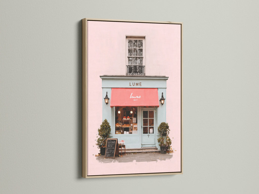 A delightful art print is showcased in an oak frame. The artwork captures a charming shop front with a pink exterior and a vibrant red awning. The oak frame enhances the artwork's warmth. This piece brings a touch of elegance to your home decor with its classic and refined style.