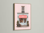 A delightful art print is showcased in an oak frame. The artwork captures a charming shop front with a pink exterior and a vibrant red awning. The oak frame enhances the artwork's warmth. This piece brings a touch of elegance to your home decor with its classic and refined style.