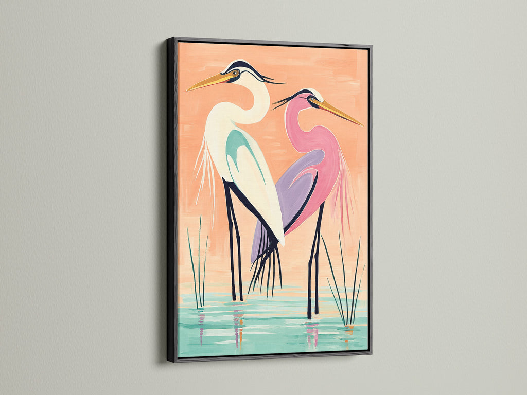 A coastal bird wall art piece featuring herons is displayed in a black frame. This black frame provides a bold contrast to the peach and teal tones in the heron art. Ideal for creating a focal point in any room. This artwork is perfect for homeowners renters interior designers and business owners.