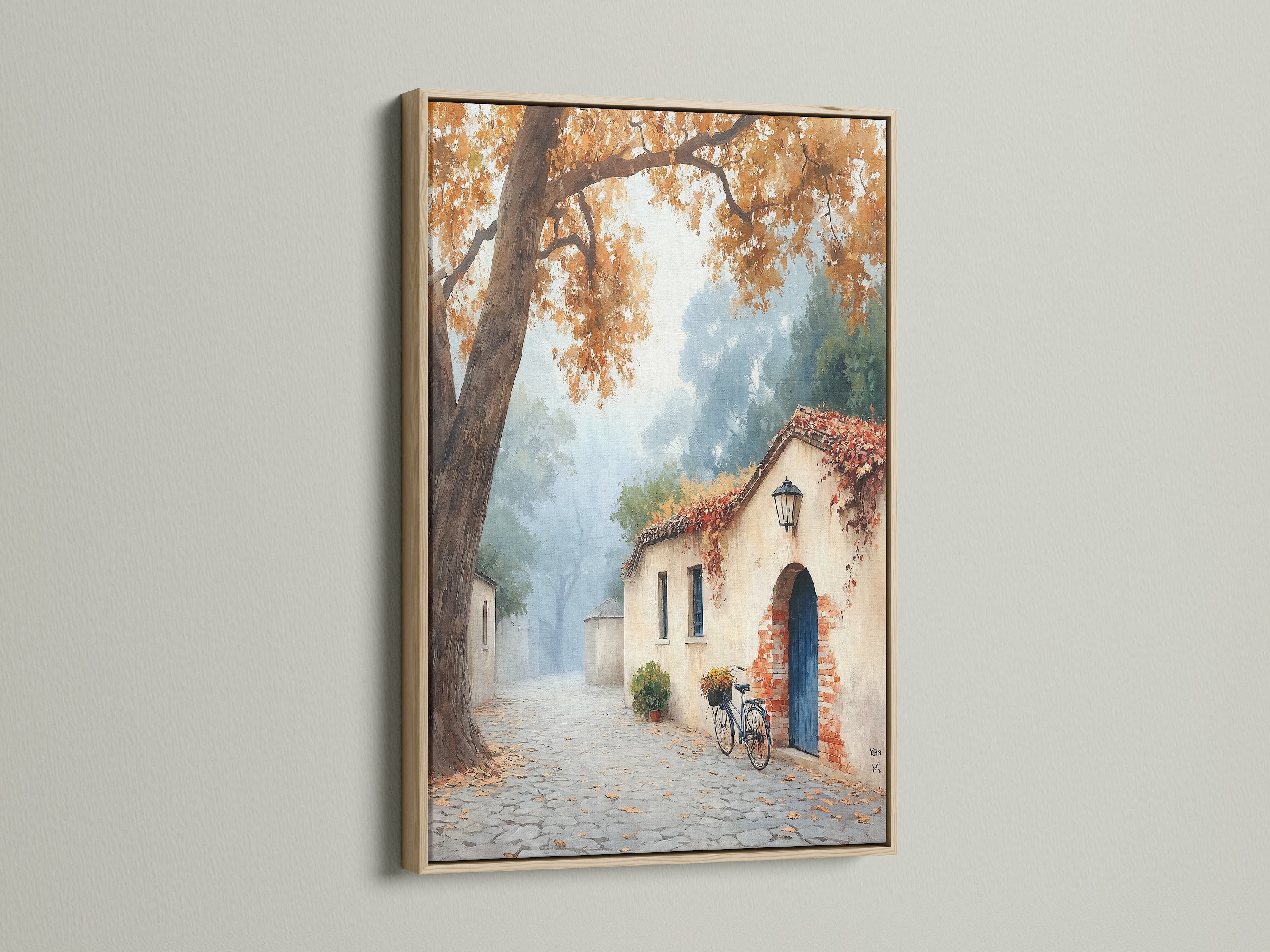 Italian Village artwork displayed in an oak frame. This autumn landscape adds a touch of European charm to your space. The oak frame enhances the vintage wall art. It is ideal for rustic home decor. Notice the cobblestone street and bicycle art.