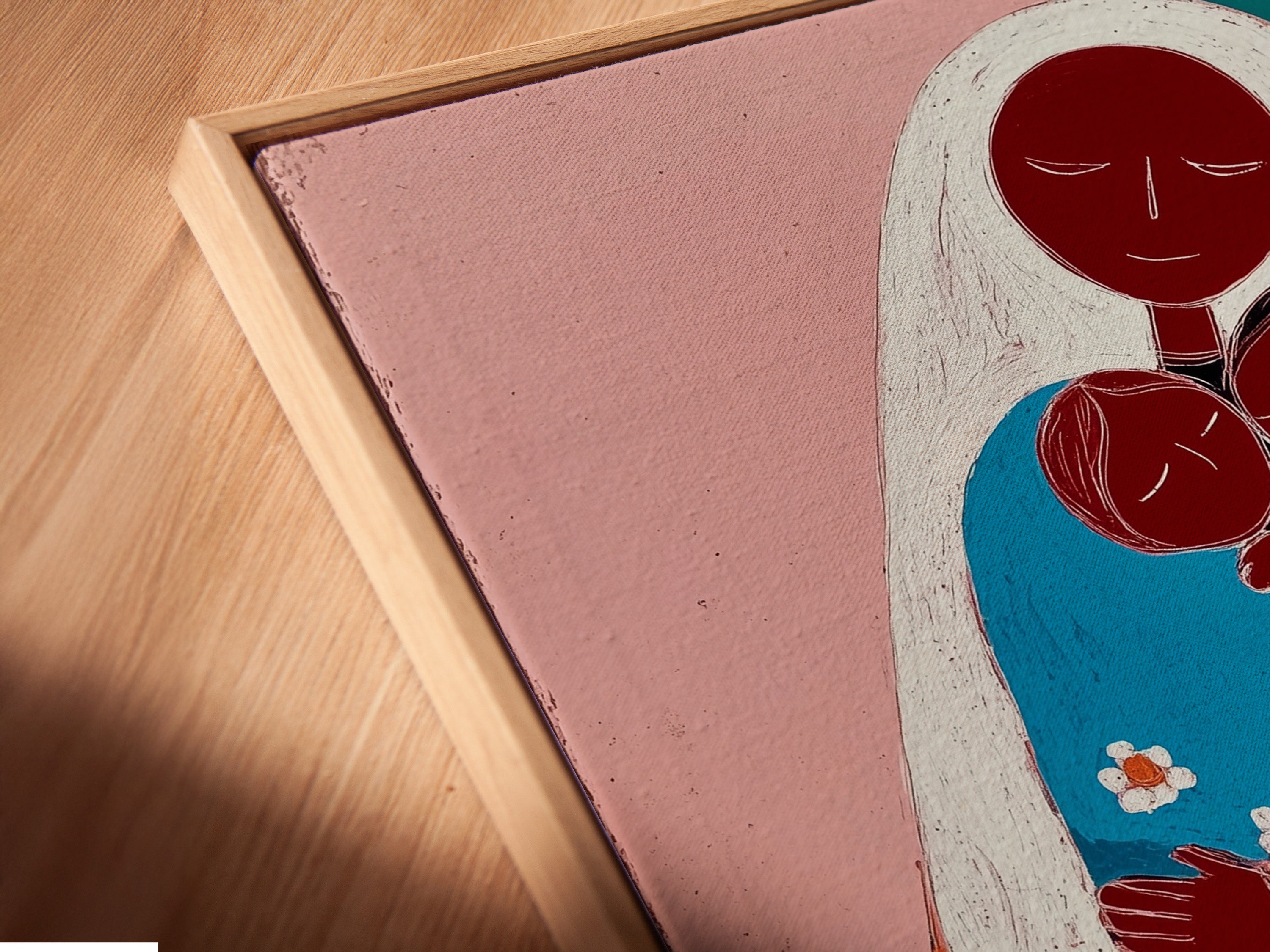 Close-up of a canvas print in a floating frame. The art showcases a mother embracing two children. The floating frame enhances the artwork's depth. This is a modern and stylish way to display your favorite pieces. The art is on a white wall.