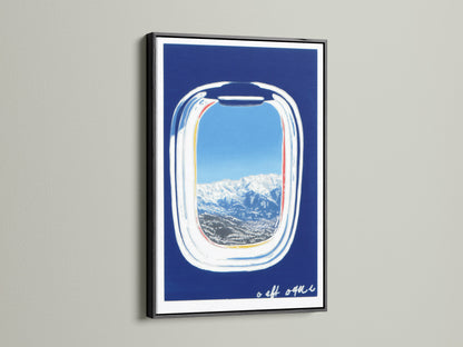 Artwork featuring an airplane window view in a black frame. The print offers a scenic landscape with snow-capped mountains and a blue sky. This modern travel art is a wanderlust decor piece. A unique aviation art piece.