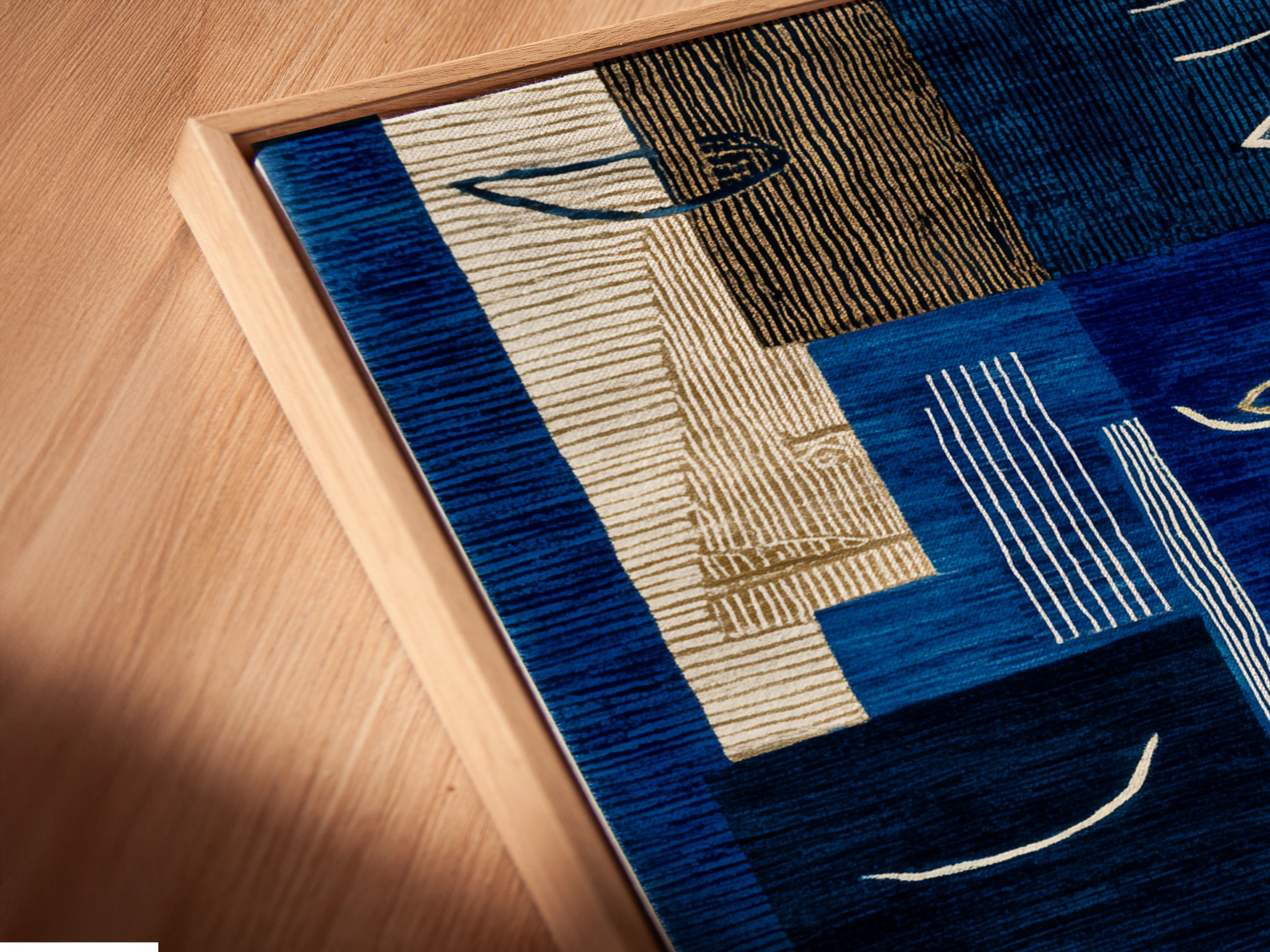 A close-up angled view of a canvas print in a floating frame. The abstract blue art is highlighted beautifully. The modern geometric artwork enhances any space. Perfect contemporary wall decor for refined interiors. The navy and cream tones complement any style