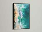 The ocean waves canvas print is showcased in a black frame. This provides a striking contrast. The artwork features aerial photography of turquoise teal waves. A great piece for coastal themed interiors.