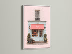 This art print is elegantly presented in a white frame. The artwork depicts a lovely building with a pink front and a striking red awning. The white frame offers a clean modern look. It allows the artwork’s colors to truly stand out. This piece is a chic addition to any space.