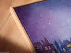Angled close up of a canvas print in a floating frame. The artwork showcases a whimsical cityscape under a starry sky. The buildings have glowing windows. The floating frame gives the art a modern look. It enhances the overall aesthetic of the piece. This artwork is sure to be a conversation starter.