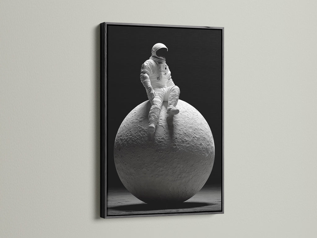 A dramatic art print features an astronaut sitting on the moon. The artwork is framed in a sleek black frame. The black frame adds contrast and sophistication. It enhances the overall impact of the artwork in the space.