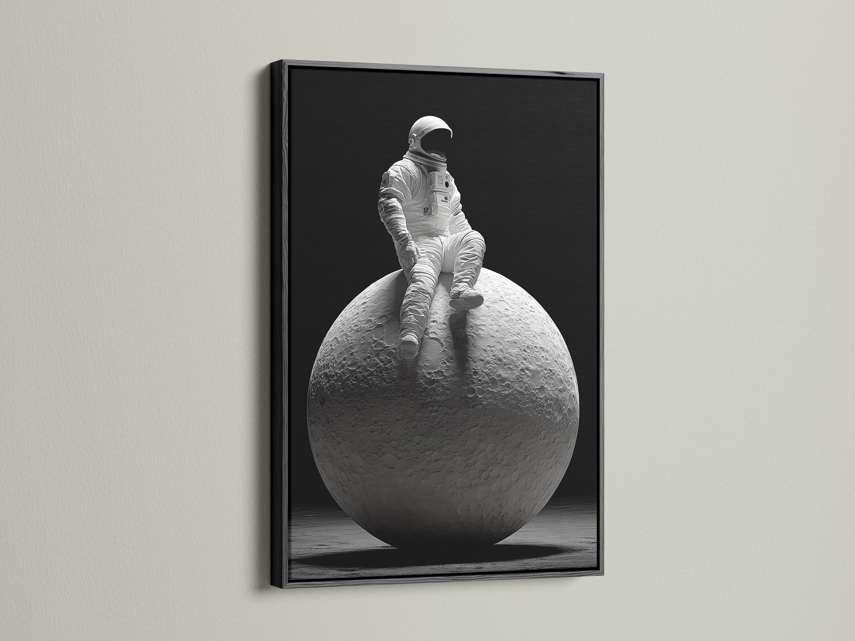 A dramatic art print features an astronaut sitting on the moon. The artwork is framed in a sleek black frame. The black frame adds contrast and sophistication. It enhances the overall impact of the artwork in the space.