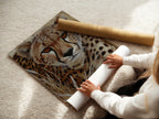 A woman is carefully rolling a fine art poster paper. The paper is a high-quality print of the cheetah portrait. This ensures safe handling and preservation of the artwork. Perfect for those who appreciate fine art and detail.