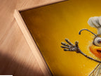 A close-up angled view of the Chef Bee canvas print in a floating frame. The funny kitchen art is visible in detail. This bee artwork is perfect for dining room decor. View the textures and craftsmanship.