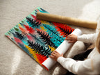 A woman is carefully rolling a fine art poster paper. The artwork is a colorful forest print. This abstract tree wall art is perfect for any room. Modern woodland artwork for bedroom decor. The nature print is ideal for adding scandi decor. Get your own tree canvas or forest art today. It enhances any space.
