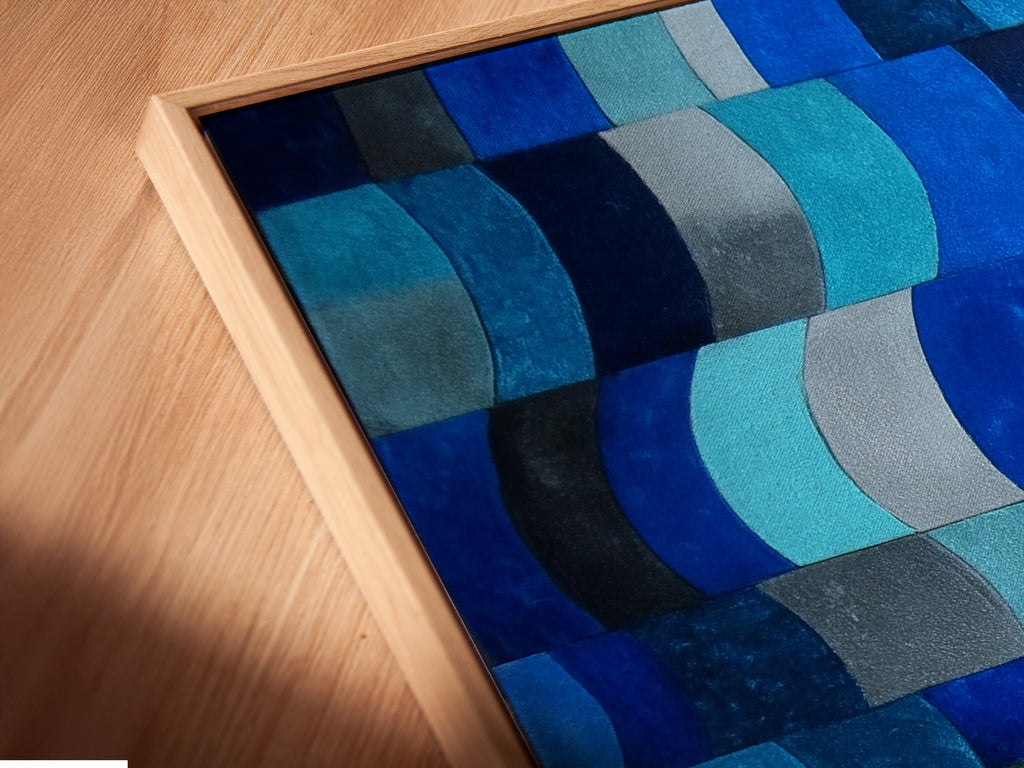 A close-up angled view of a canvas print in a floating frame is presented. The floating frame enhances the modern abstract art. The indigo navy print stands out beautifully. Perfect for adding a contemporary touch to any room. This geometric wall art is ideal for coastal home decor.