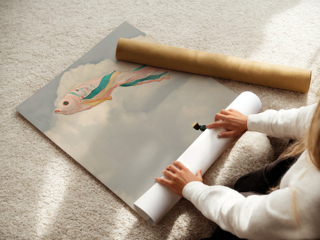 A woman rolls a fine art poster paper. The artwork features a surreal fish kite. The dreamy wall art is a whimsical print. Perfect for adding a unique touch to any room.