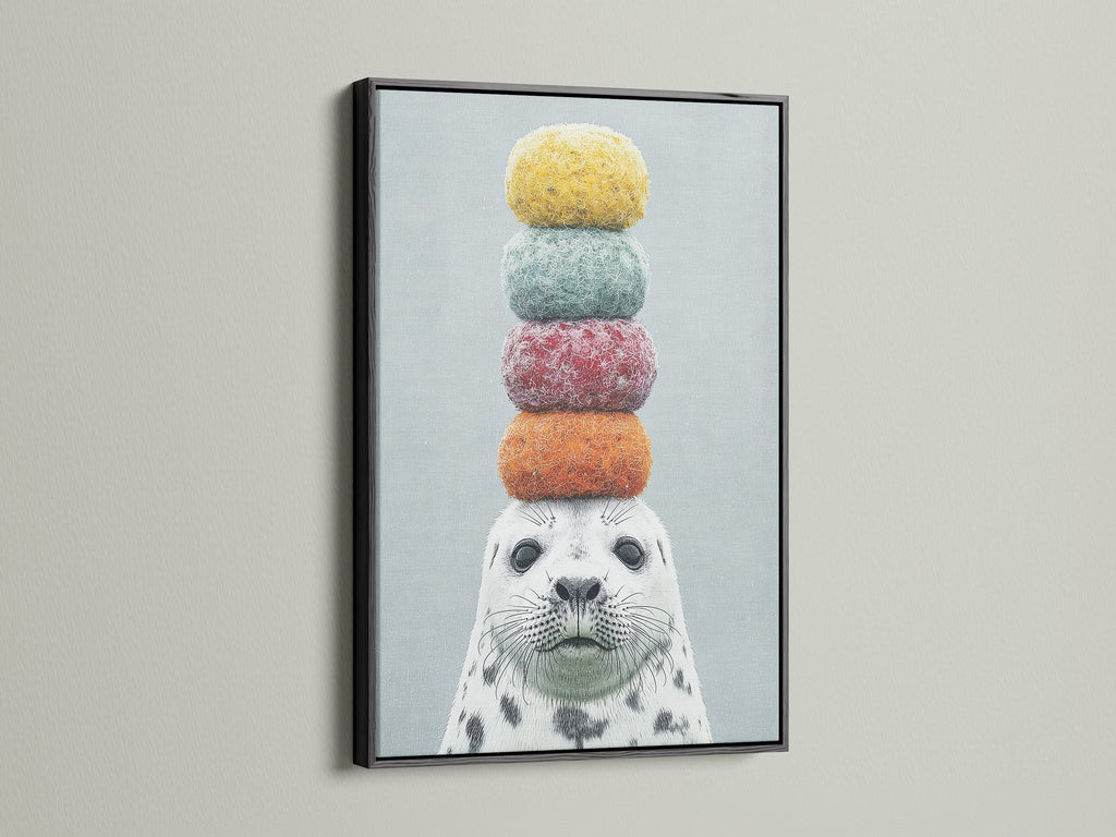 Framed whimsical seal artwork with colorful macarons on its head. The art is presented in a modern black frame. A fun and quirky addition to any space. This animal canvas art is ideal for kids rooms or coastal themed decor. Explore our playful art print collection.