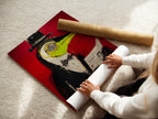 A woman is carefully rolling a fine art poster paper. Preparing a surreal bird artwork print. The contemporary red abstract is ready for framing. Perfect for modern animal art lovers.