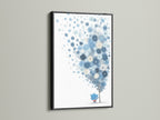 The blue floral canvas print is beautifully contrasted by a sleek black frame. This pairing makes the pastel botanical art pop. The whimsical flower tree art is a perfect addition to a modern nursery. It brings a touch of elegance and charm.