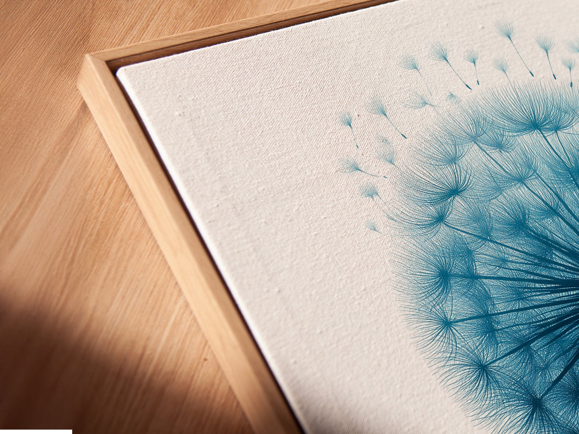 A close-up angled view of a dandelion canvas print in a floating frame. The floating frame adds depth to the artwork. Minimalist floral artwork for bedroom decor. A beautiful flower nature print. Blue home decor.