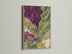 A captivating artwork is showcased in an oak frame. The frame enhances the topographical map. Notice the purple and green details. The artwork is displayed on a clean white wall. This piece brings a touch of nature indoors. It is a great addition to your art collection.