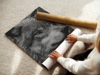 A woman is carefully rolling a fine art poster paper of the wolf portrait. Ensuring top-notch quality for your wildlife art. Get ready to display this stunning animal artwork. Perfect for nature lovers and art enthusiasts.
