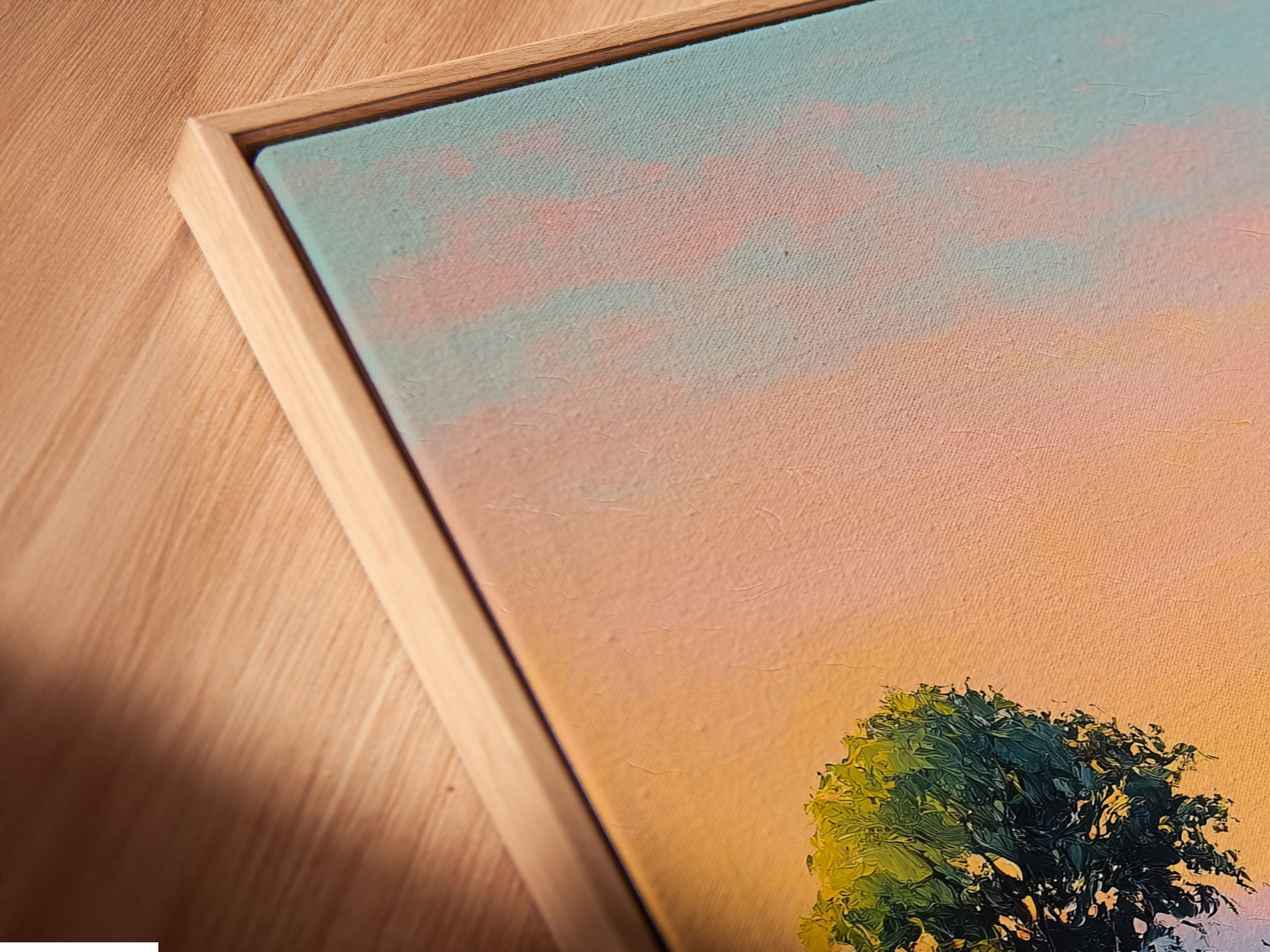 A close-up angled view of a canvas print in a floating frame. The sunset landscape artwork features a golden path print. This type of frame adds a modern touch to the nature wall decor. Ideal for homeowners and new couples. It brings soothing vibes to any space.