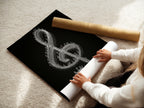 A woman carefully rolls a fine art poster paper. This musical artwork is ready for framing. The treble clef print is a modern masterpiece. It is perfect for music enthusiasts. The poster paper ensures high-quality reproduction. This makes it a unique gift.