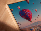 Close-up angled view of a canvas print in a floating frame. The Cappadocia landscape artwork appears to float. The floating frame adds a modern touch. It enhances the travel photography for bedroom decor.