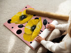 A woman is carefully rolling a fine art poster paper. This high-quality paper is perfect for botanical prints and floral artwork. The Yellow Poppy artwork will look stunning. Ideal for modern bedroom wall decor.
