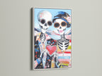 Day of the Dead wall art in a white frame. The sugar skull couple poster brings a vibrant folk art touch. The colorful art and gothic decor make it ideal for a home altar or eclectic living room.
