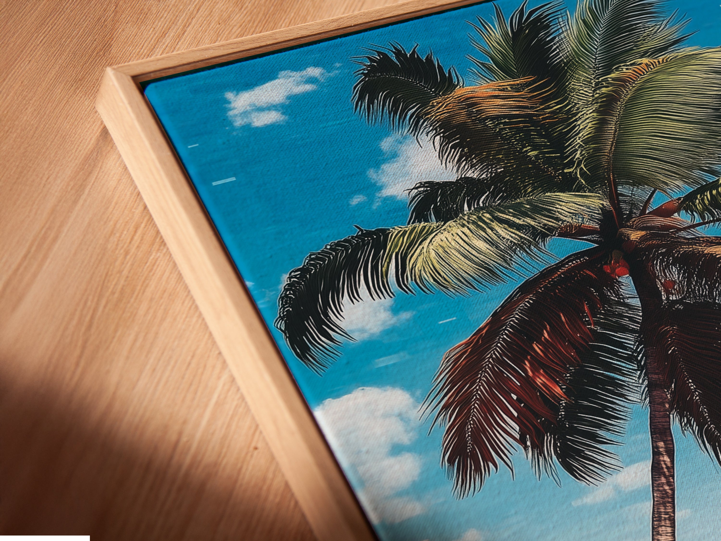 Angled close up of a canvas print in a floating frame. The tropical beach artwork features a palm tree pink sand and turquoise ocean. This coastal wall art enhances any space with summer vibes.