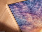 A close up angled view of a Harbor Sunset canvas print in a floating frame. The artwork features fishing boats under a colorful sunset sky. The floating frame adds depth and dimension to the piece. This coastal wall art is perfect for creating a serene focal point in any room. The beige and blue tones complement various decor styles.