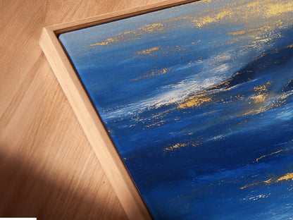 Close-up angled view of a canvas print in a floating frame. The Ocean Reflection art features blue and gold abstract seascape details. The floating frame gives the artwork depth and dimension. A stylish addition to any modern or coastal space.