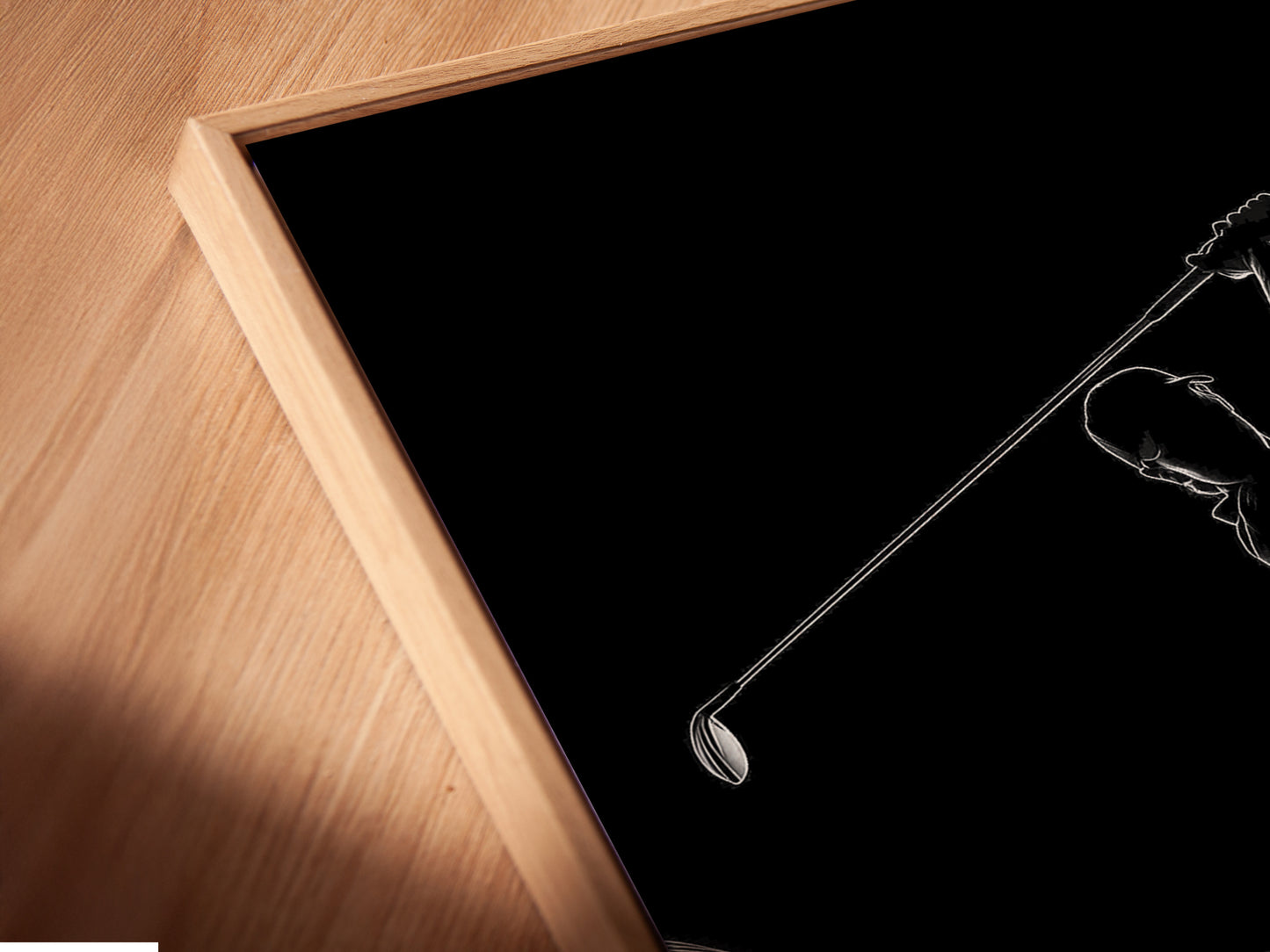 A close-up shows a canvas print in a floating frame. The golfer artwork appears to hover. The floating frame adds depth and dimension to the minimalist sports art. Ideal for a modern office or stylish man cave.