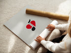 A woman is carefully rolling a fine art poster paper. This ensures the music art arrives in perfect condition. The red and black minimalist print is ready to frame. It's a great gift for music enthusiasts.