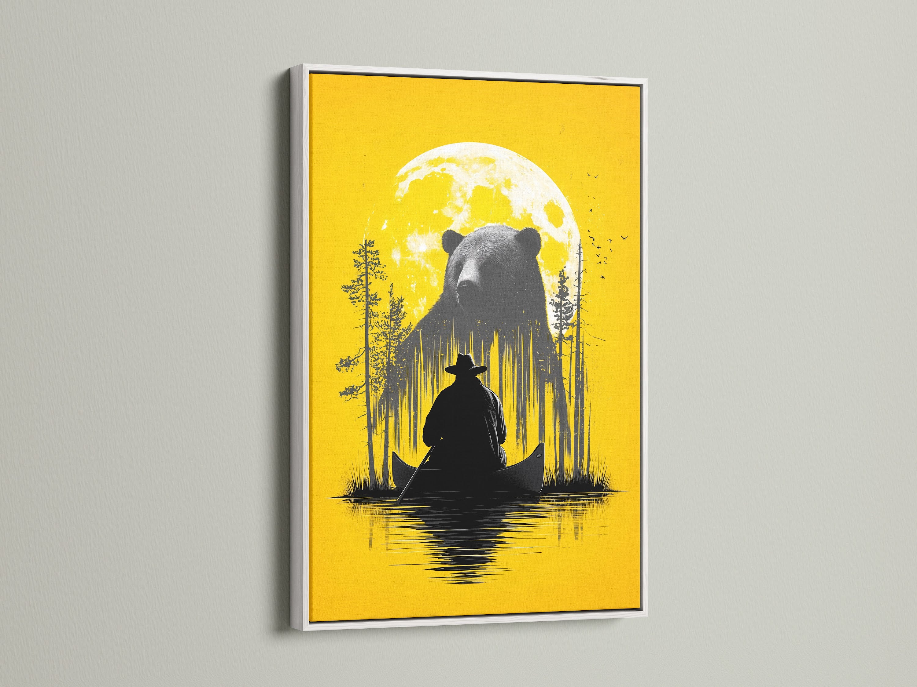 Framed Bear and Canoe artwork is displayed. The frame is a white frame. It is a rustic nature wall art. It shows a bear and a canoe under a yellow moon. Ideal for cabin decor and adventure art lovers. The white frame offers a clean modern look. It is perfect for a living room bedroom or study.