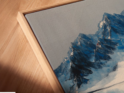 Angled close up of a mountain reflection canvas print in a floating frame.  The indigo blue lake wall art is perfect for modern office decor.  The floating frame enhances the landscape artwork. Its reflection print adds a touch of winter to any space. This is a great mountain painting.
