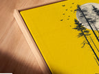 A close-up angled view reveals a canvas print of the bear and canoe artwork set in a floating frame. The yellow moon wall art radiates from within the frame. Notice the fine details and craftsmanship of this nature silhouette print. This piece adds elegance to cabin decor.