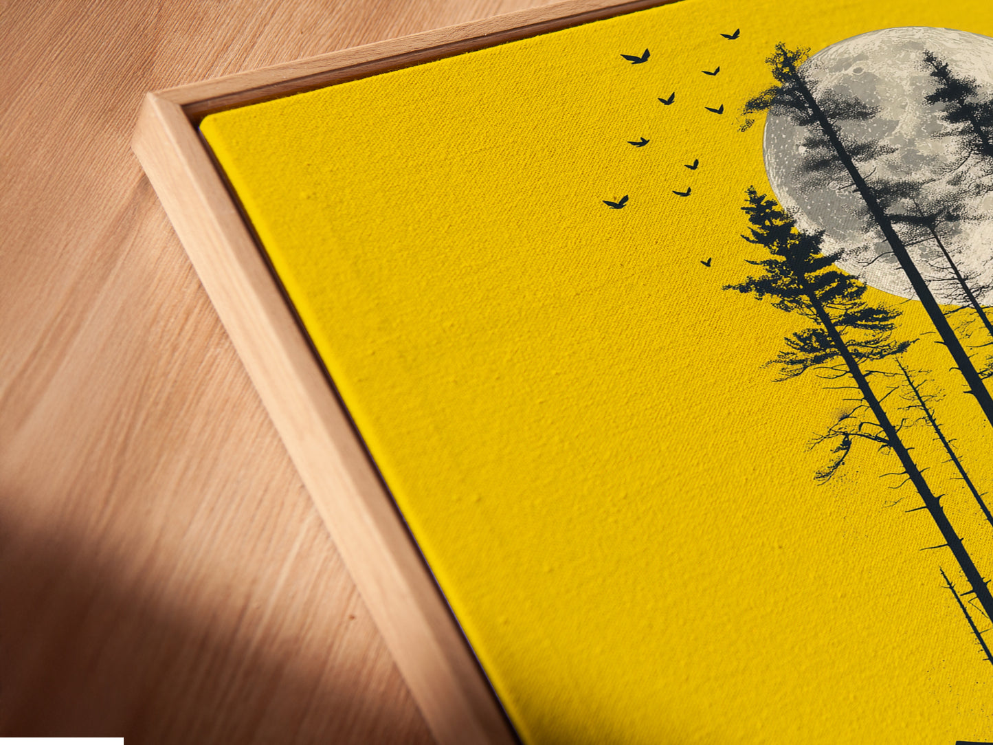 A close-up angled view reveals a canvas print of the bear and canoe artwork set in a floating frame. The yellow moon wall art radiates from within the frame. Notice the fine details and craftsmanship of this nature silhouette print. This piece adds elegance to cabin decor.