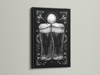 A framed artwork is on display. The art is in a black frame. The artwork features a monochromatic illustration of two beer glasses. The beer glasses are the focal point. The print adds a touch of elegance to any room.  The black frame offers a bold touch.