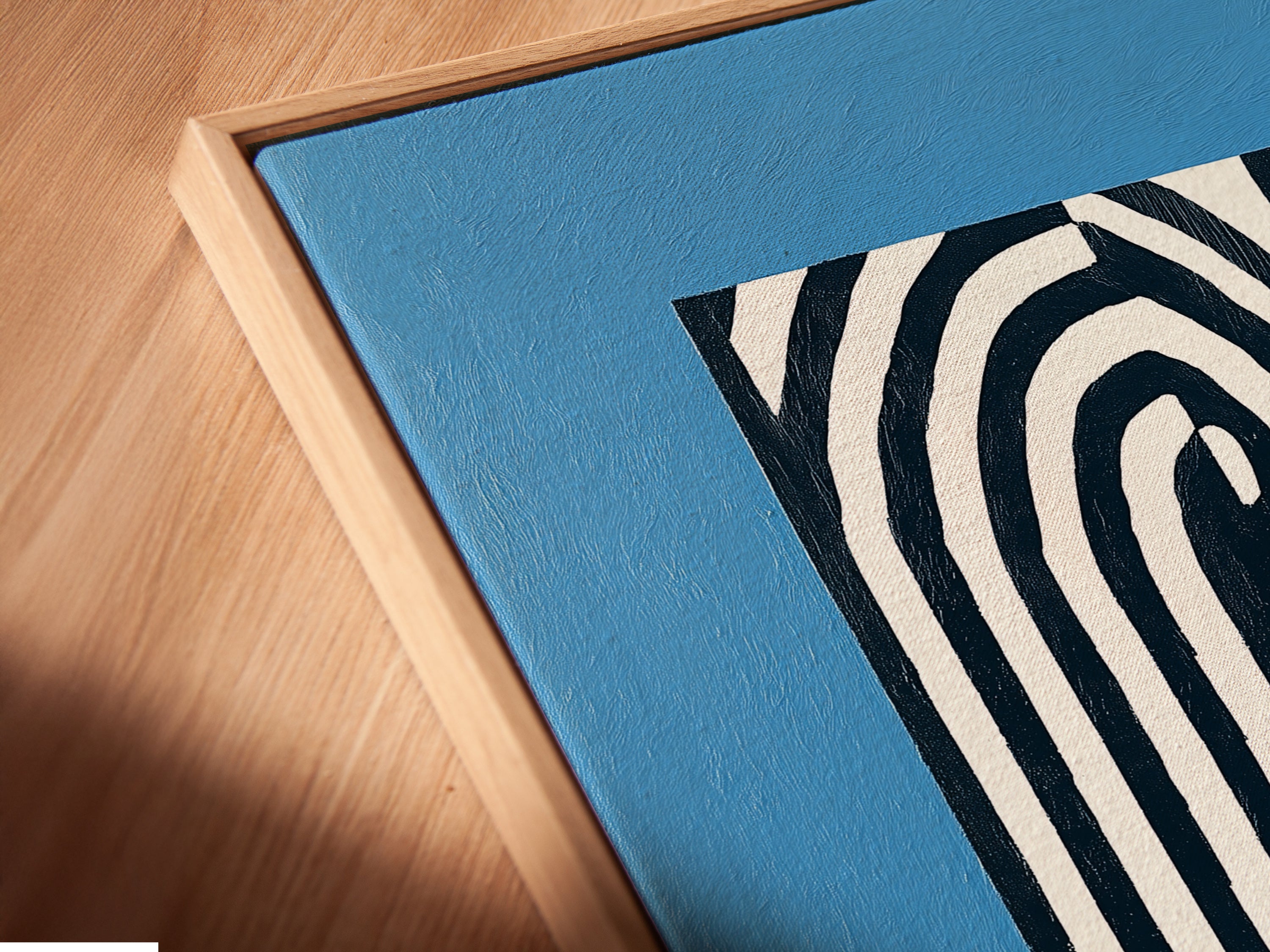 Close-up of a canvas print in a floating frame. The abstract lines and blue backdrop create a modern look. This minimalist artwork enhances any room. Perfect for contemporary decor. See the details of our framed canvas prints now.