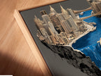 A close-up angled view reveals a canvas print in a floating frame. The surreal city waterfall artwork captivates the eye. This contemporary urban piece enhances modern decor. The floating frame adds a unique touch to the architectural artwork. The fantasy cityscape brings a modern aesthetic.